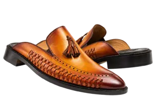 Cognac leather tassel mules showing the smooth vamp, perforated apron border and woven panels
