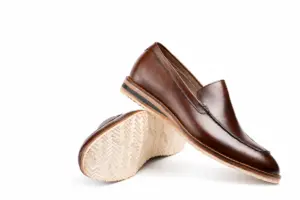 Crossed brown apron-toe loafers showing the leather upper and cream chevron tread