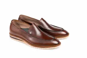 Three-quarter view of brown leather apron-toe loafers showing the raised seam and cream soles