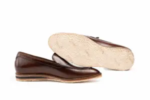 Cream Vibram outsole with repeated chevron tread beneath a brown leather loafer