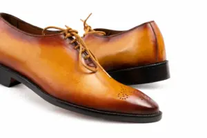 Close-up of the tan Oxford laces, burnished leather and perforated toe medallion
