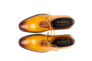 Overhead view of tan wholecut Oxfords showing matching laces and perforated toe medallions