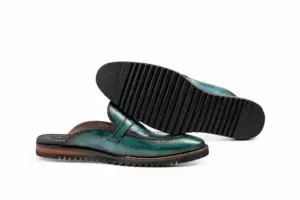 Black ridged Vibram outsole beneath a teal patina buckle mule