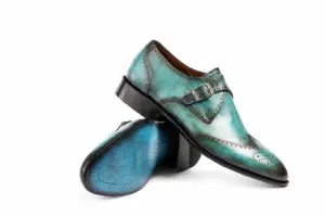 Crossed turquoise patina wingtip single monk strap shoes showing the upper, outsole and heel