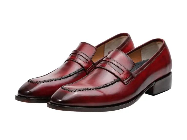 Pair of red-burgundy patina penny loafers showing stitched apron and penny straps
