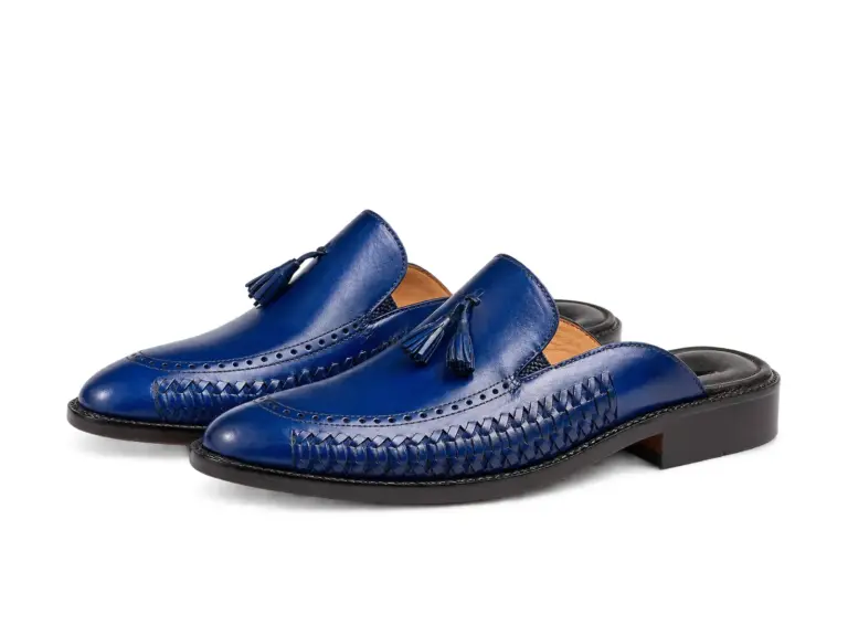 Three-quarter view of royal blue handwoven tassel mules showing woven leather sides, smooth blue vamps and tassels