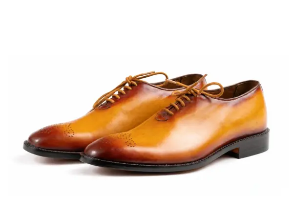 Pair of tan burnished wholecut Oxfords with darker toes and decorative medallions