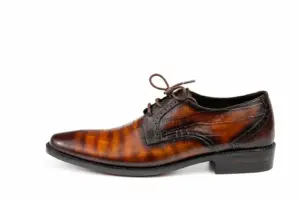 Opposite side of a tan patina croc-embossed Derby showing brogue edging at the heel seam